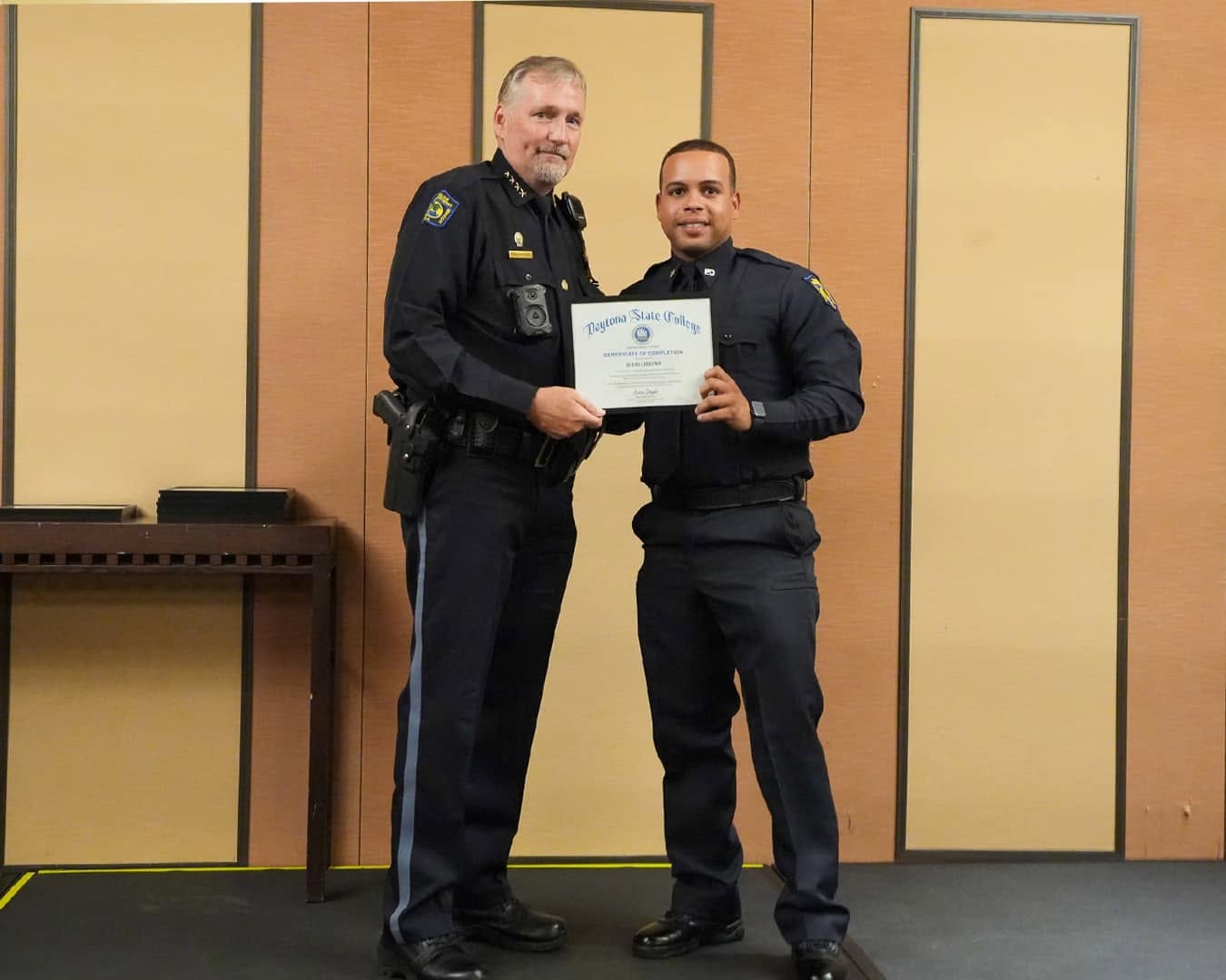 Officer Julio Liriano, right, holding a Daytona State College certificate with another officer